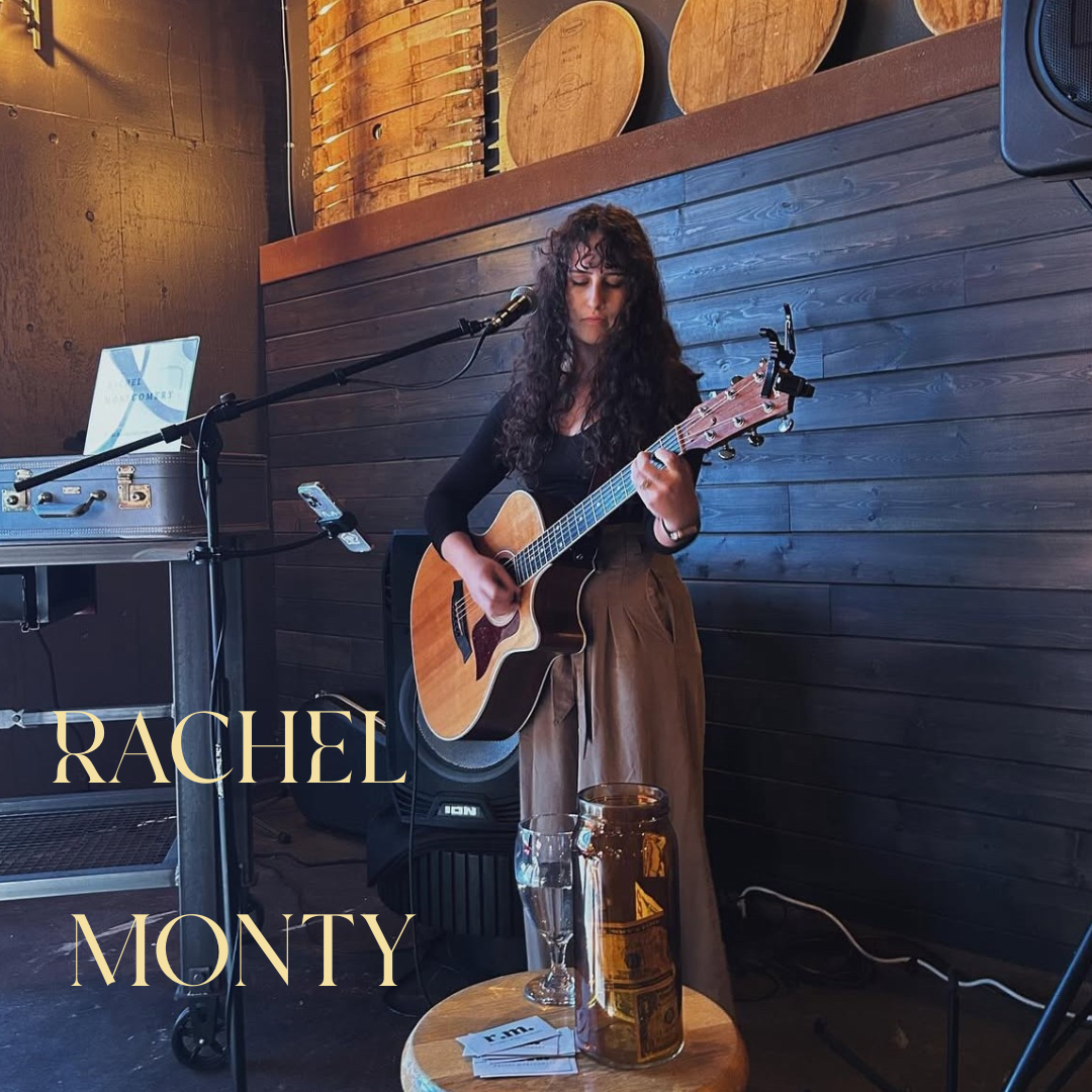 Woman with curly hair playing an acoustic guitar and singing onstage in a cozy wooden venue. Text reads Rachel Monty.