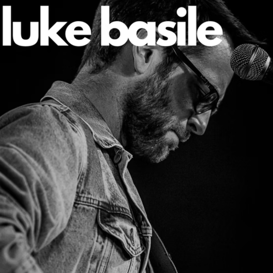 Black and white photo of a man playing guitar near a microphone, with luke basile written at the top.