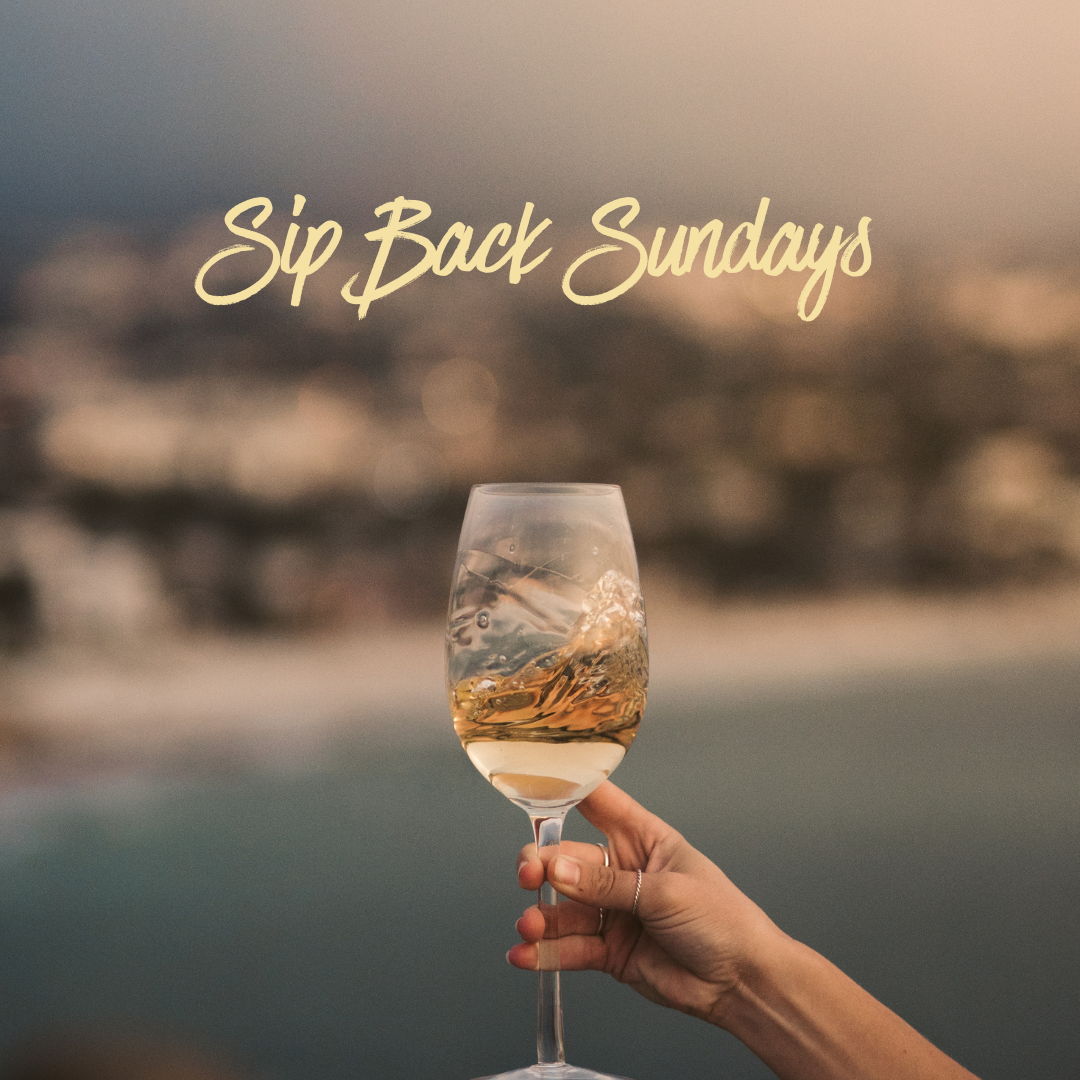 Hand holding a glass of white wine with “Sip Back Sundays” text, set against a blurred outdoor background—perfect for celebrating those relaxing sip back Sundays.