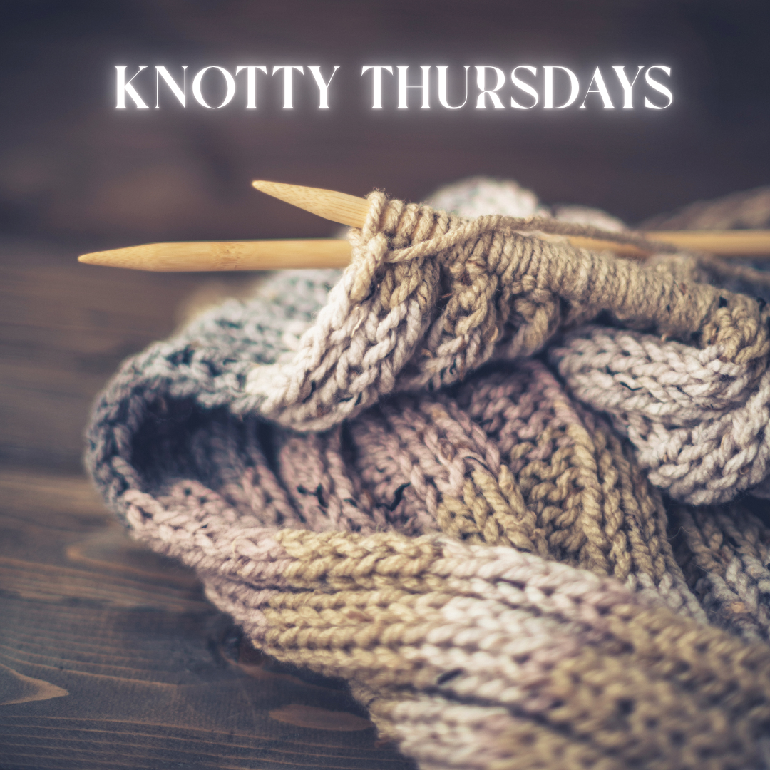 Knitting needles and yarn with the text Knotty Thursdays above on a wooden surface.