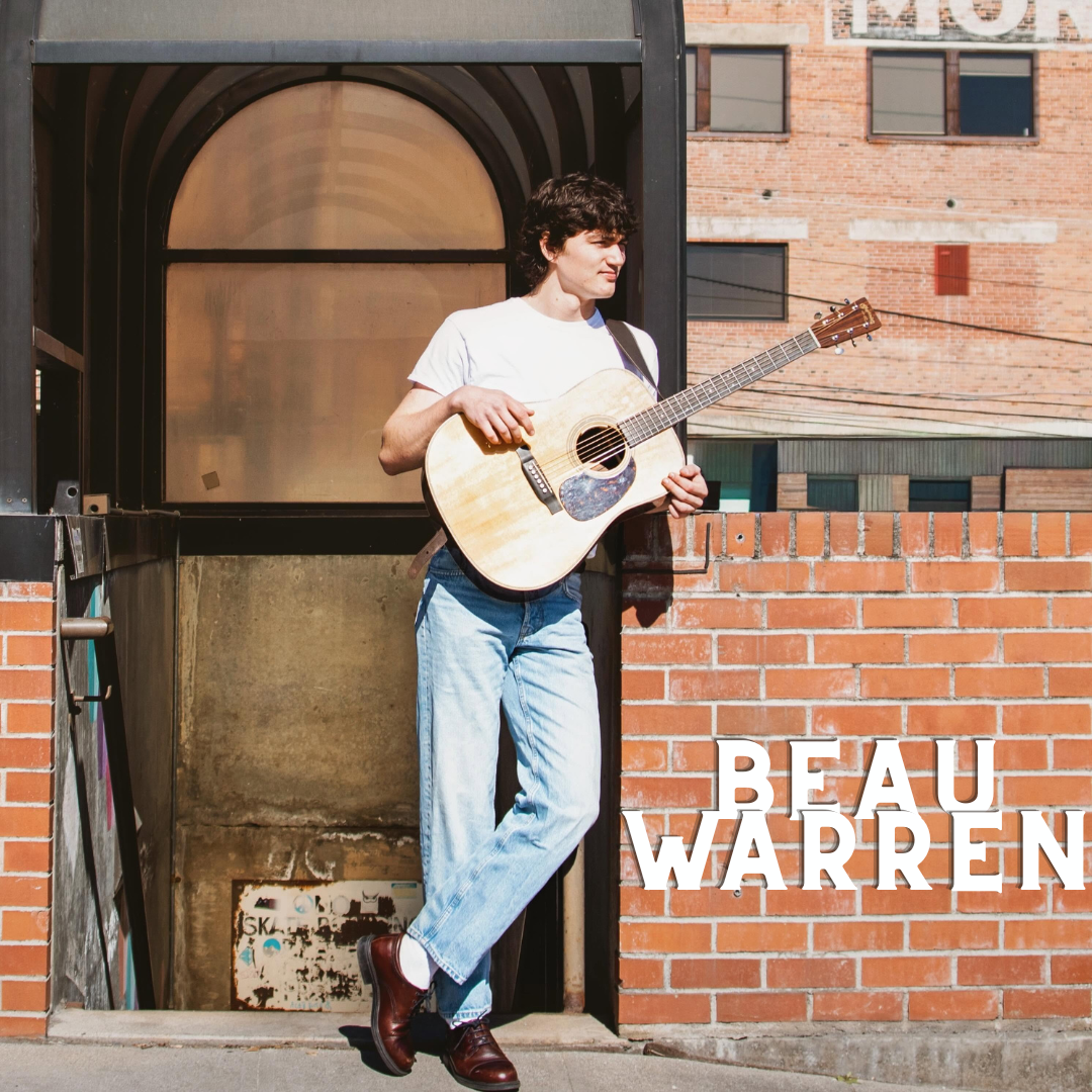 Person in jeans and white shirt holds acoustic guitar, standing by a brick wall with Beau Warren text.